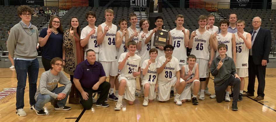 BACK TO STATE - The Okarche boys basketball team poses with the Class A Area I championship trophy after throttling Glencoe last Friday night in Enid. The Warriors are back in the state tournament for the first time since 2012. [TIMES & Article Image Alt Text