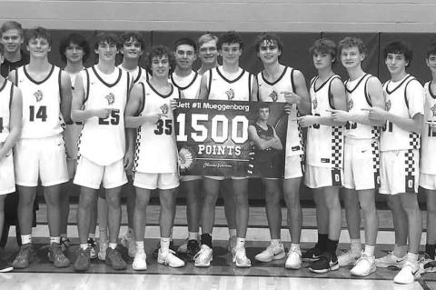 JETT MUEGGENBORG and his Okarche teammates commemorate the Warrior junior surpassing 1,500 career points during his team’s victory over Hennessey last week. Mueggenborg scored 39 points and grabbed 13 rebounds. [Photo provided]