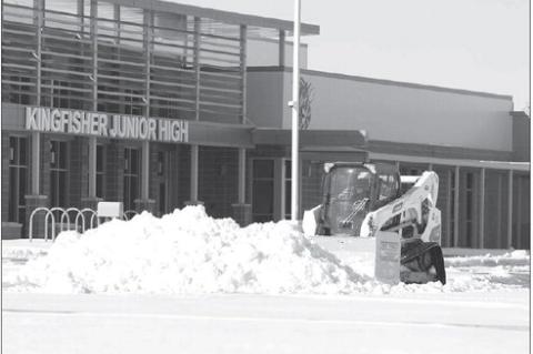 CLEANUP EFFORTS went well into the week as the county digs out from underneath several inches of snow. Jeremy Staab (top photo) spent part of his Sunday clearing downtown sidewalks, but was headed south on 13th Street Monday in freezing temperatures to as